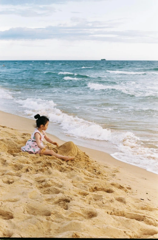 a girl sitting on the beach by the ocean