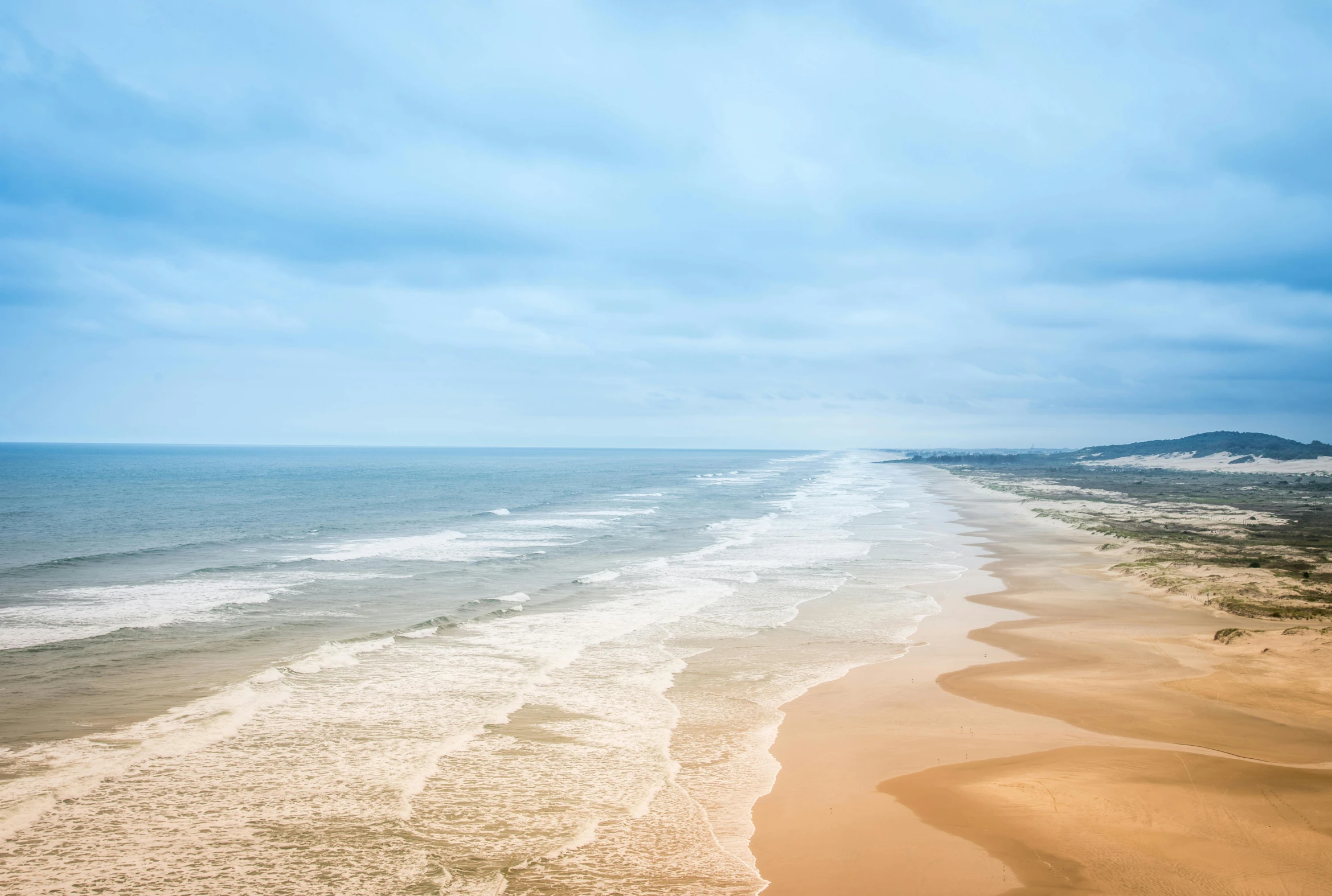 a wide beach with a few waves on top of it