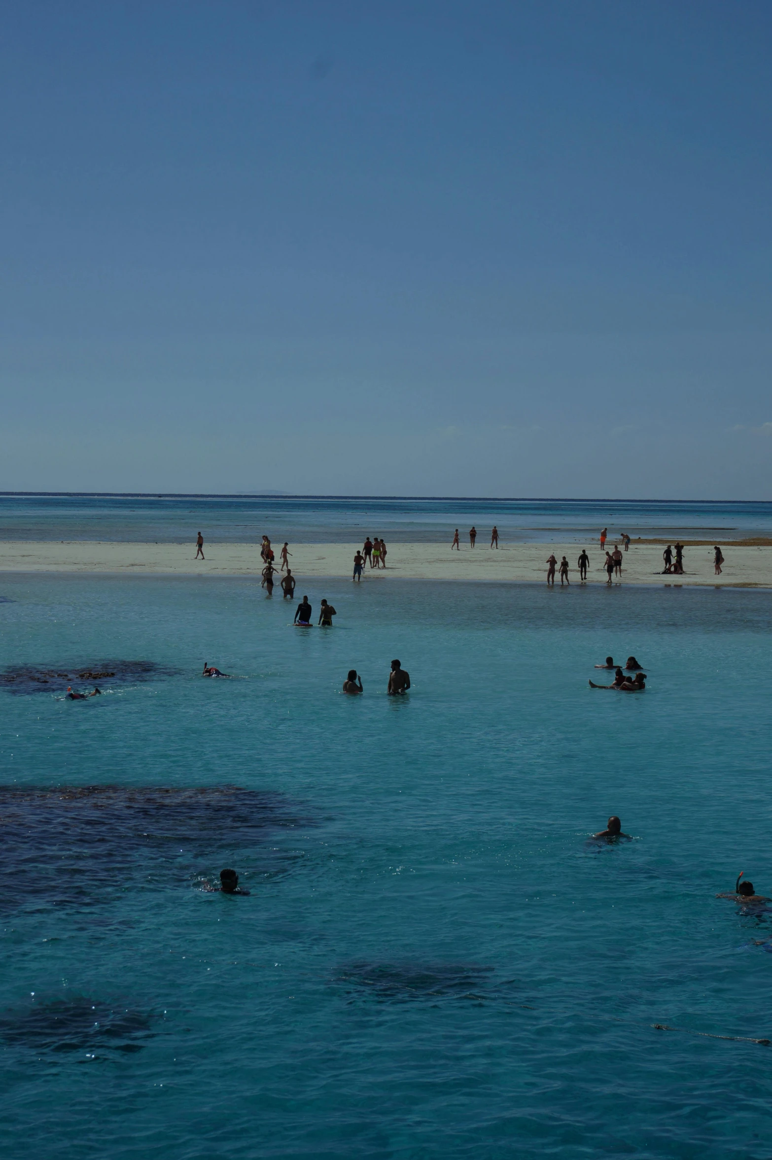 many people are riding in the sea near a beach