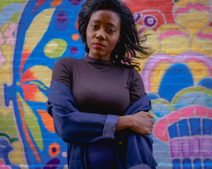 a woman is standing in front of a wall painted in colorful circles