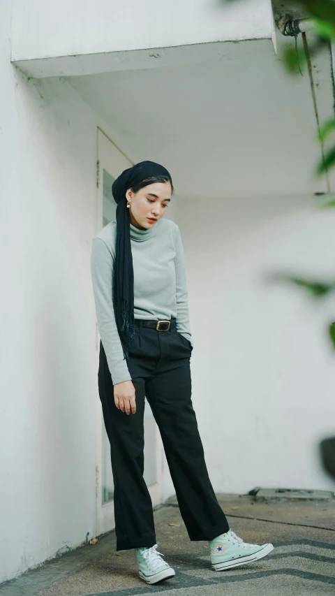 a woman in grey top and black pants wearing scarf