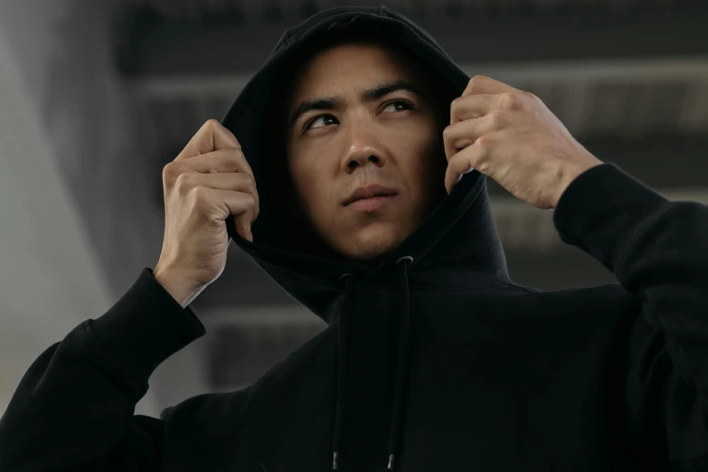 a man in black hoodie putting his hands on his ear