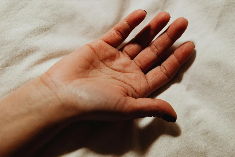 person's hand held up in the air on a bed