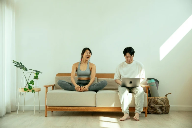 two people sitting on a couch with their laptops