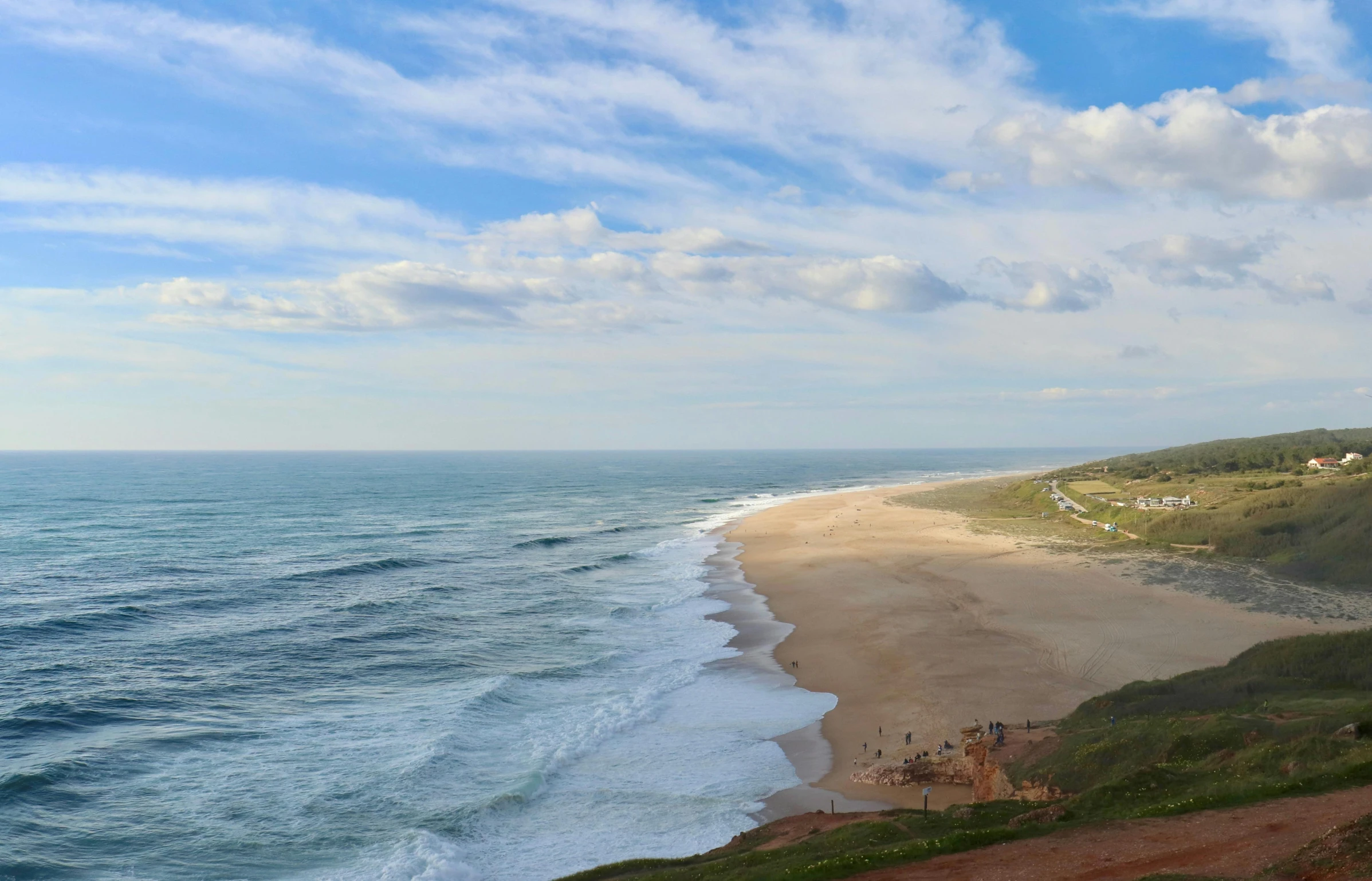 the clouds over the water and a very long stretch of beach