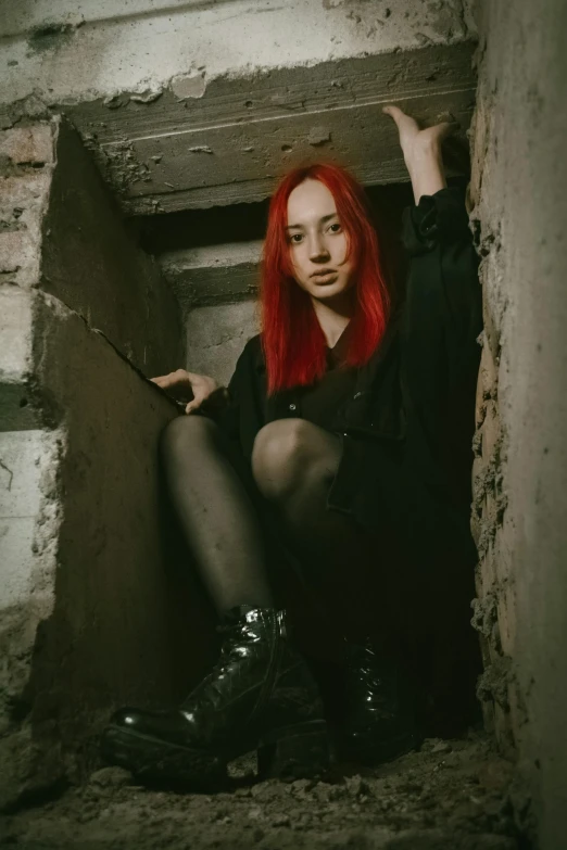 a woman with red hair is sitting in an empty cement space