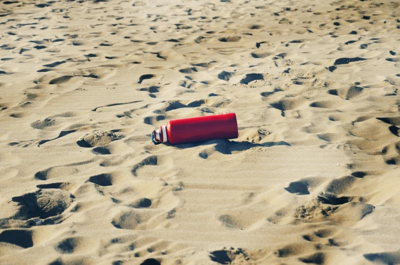 a red frisbee sitting on top of a sandy beach