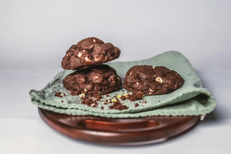 five chocolate cookies sit in a wooden bowl with one pile is on top of the other