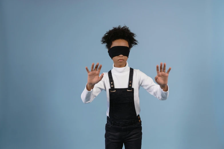 a boy wearing blind folded clothing while standing with his hands outstretched