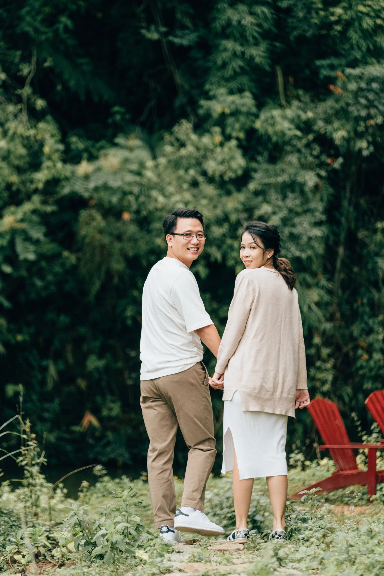 man and woman holding hands standing in tall grass