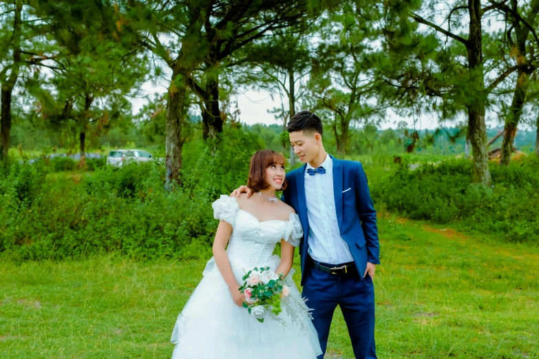 a couple in their wedding clothes standing next to each other in the grass