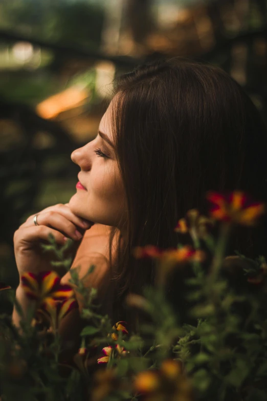 a beautiful young woman standing near colorful flowers