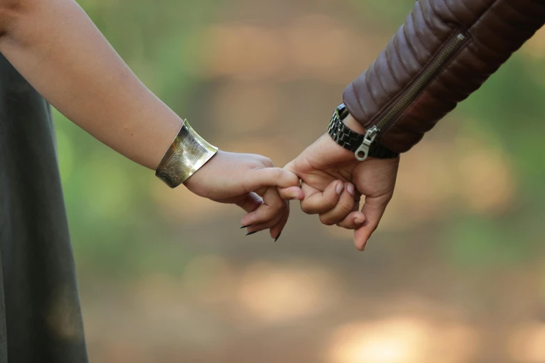 a pair of hands hold each other in front of a forest