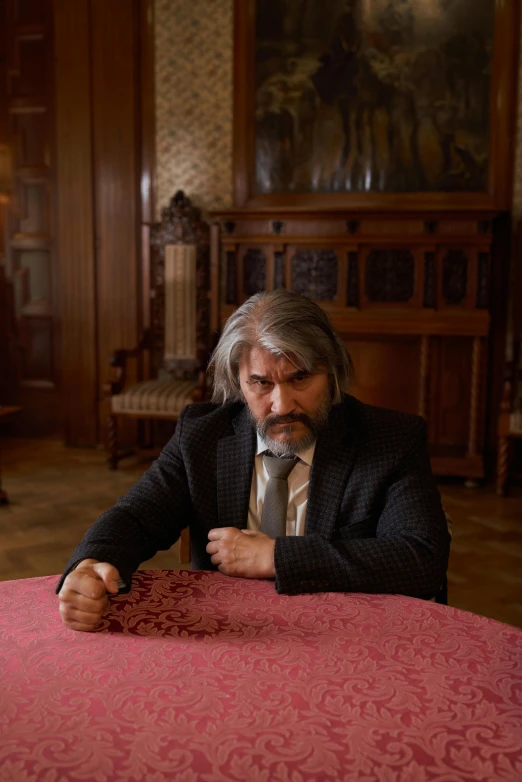 a man is sitting at a table with an elegant pink cover