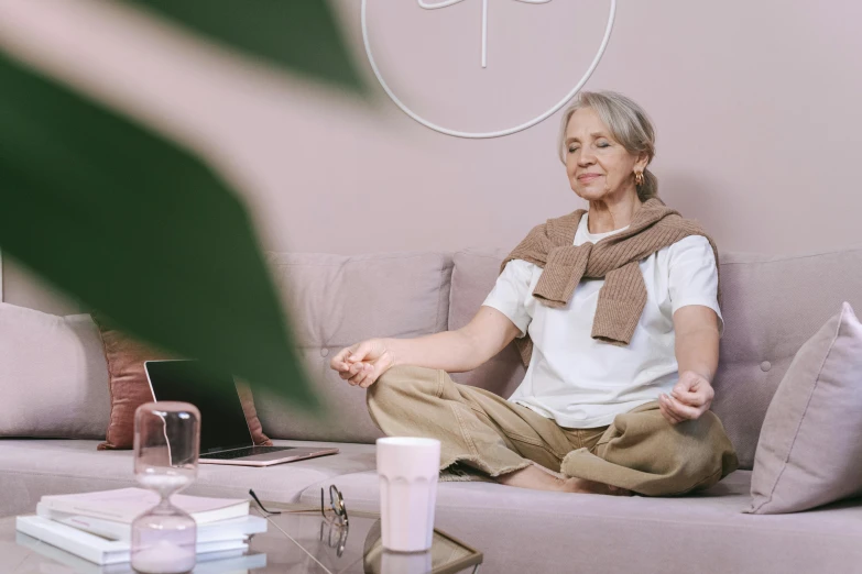 woman sitting on a couch with coffee cups and a laptop