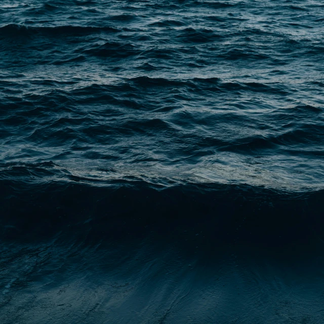 a lone boat floating on the ocean in a dark ocean