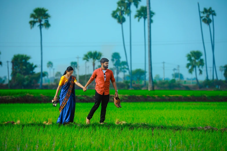 a man and woman walking across a green field