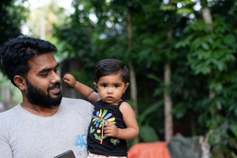 a man is holding a child while wearing a shirt
