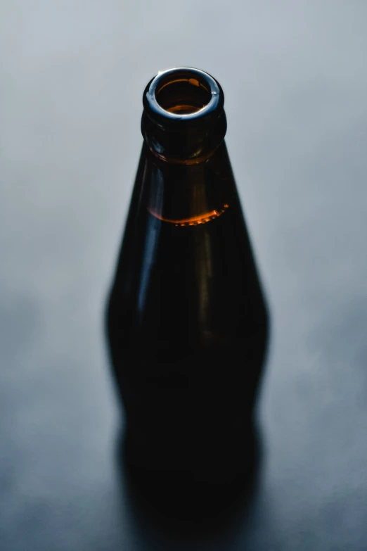 a bottle sitting on a table top, illuminated by a flashlight