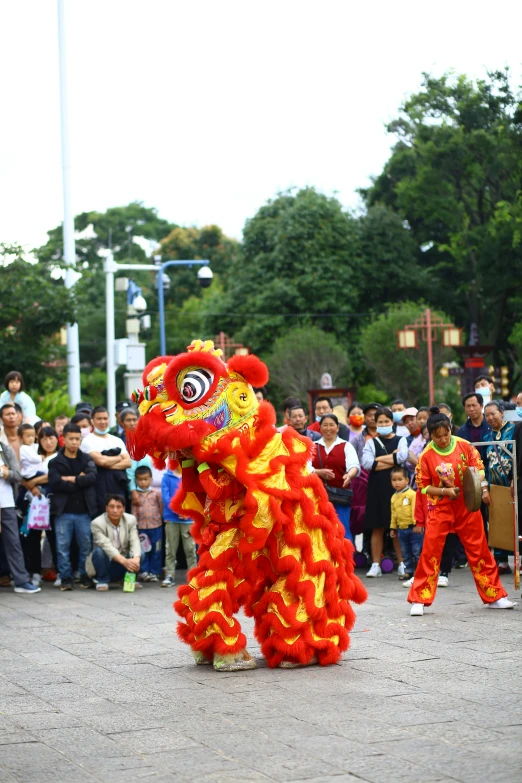 chinese lion dancers in red and orange with spectators in background