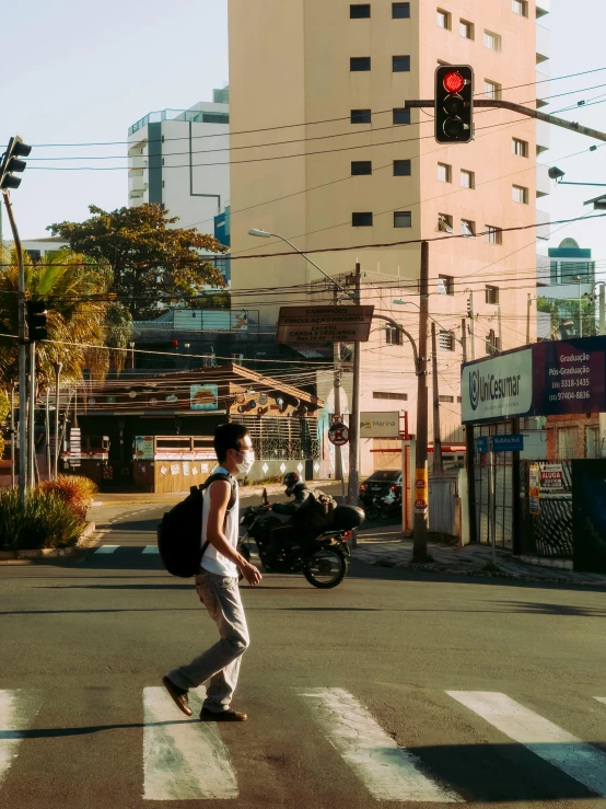 a man crossing the street at a traffic light with buildings in the background