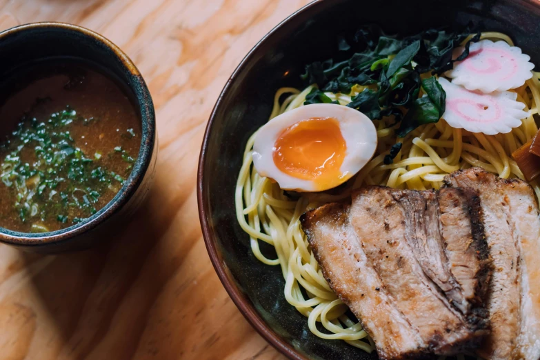 a black bowl with noodles and meat on it