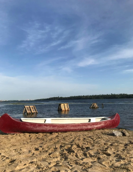 a canoe sitting on the sand by some water