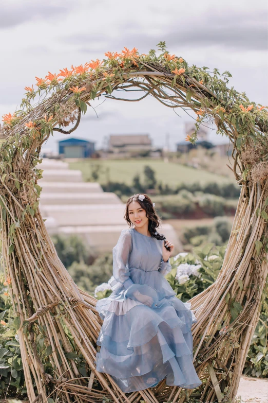 a girl in a dress is sitting on a nest made of sticks