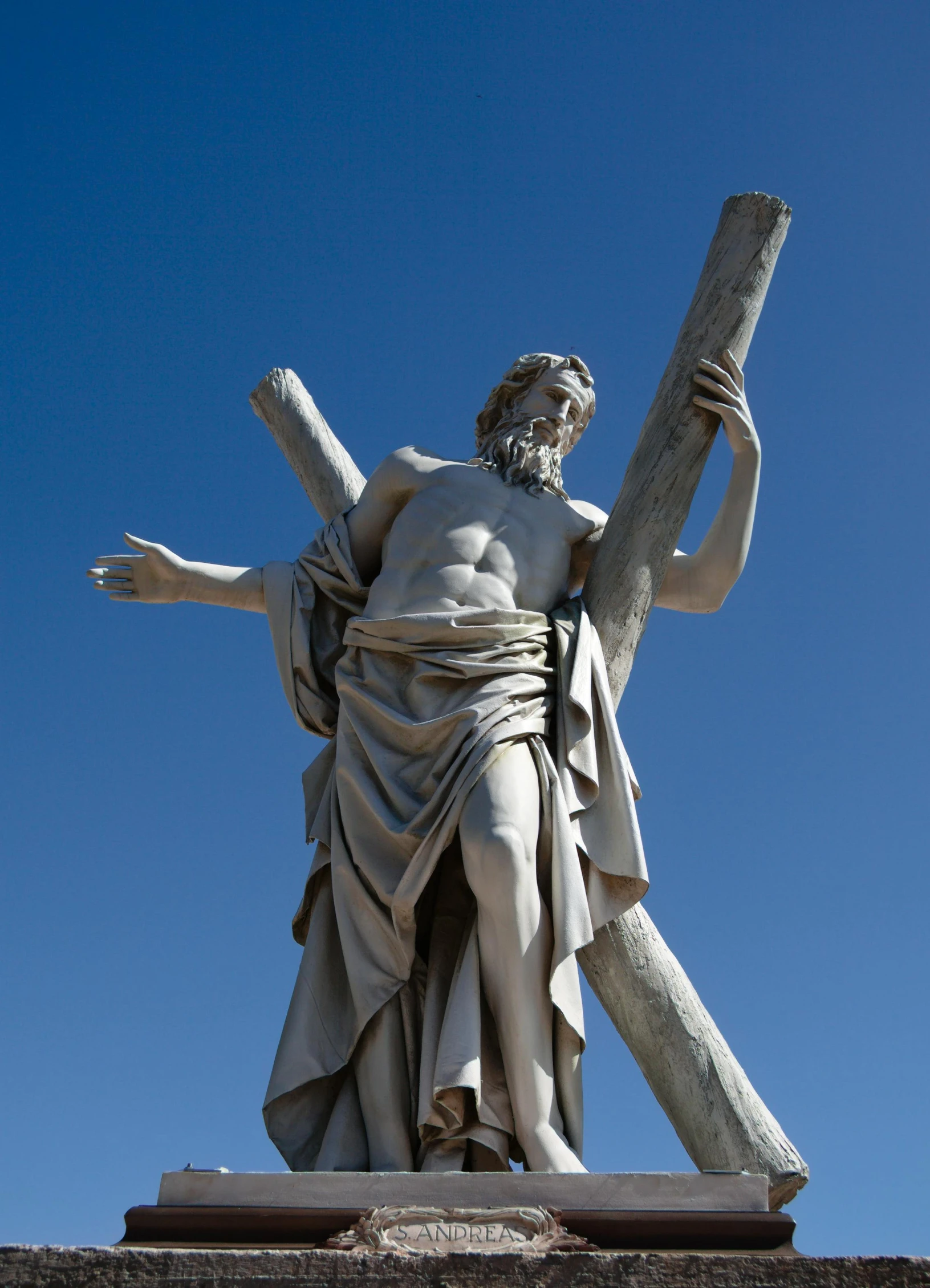 a statue is holding a cross with the arms of his hands