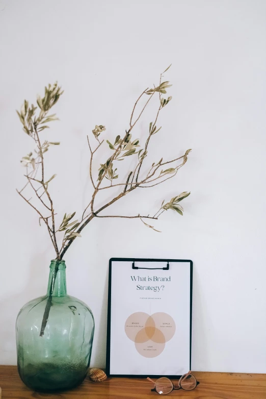 a vase with a plant in it sitting next to a picture