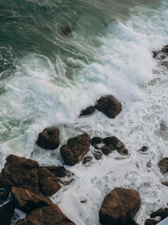 there is a bird flying over the rocks on the water