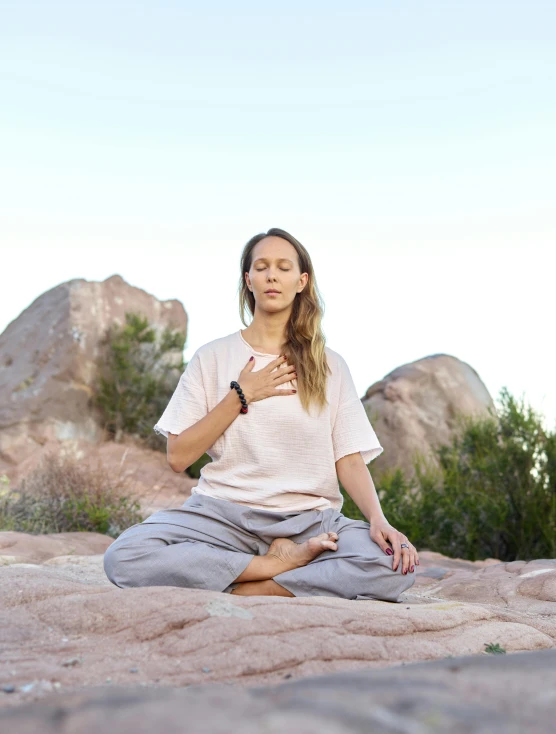 a person sitting in a meditation position on some rocks