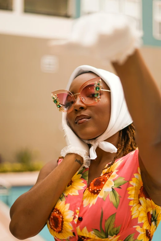 a woman with sun glasses and a hijab is in front of a swimming pool