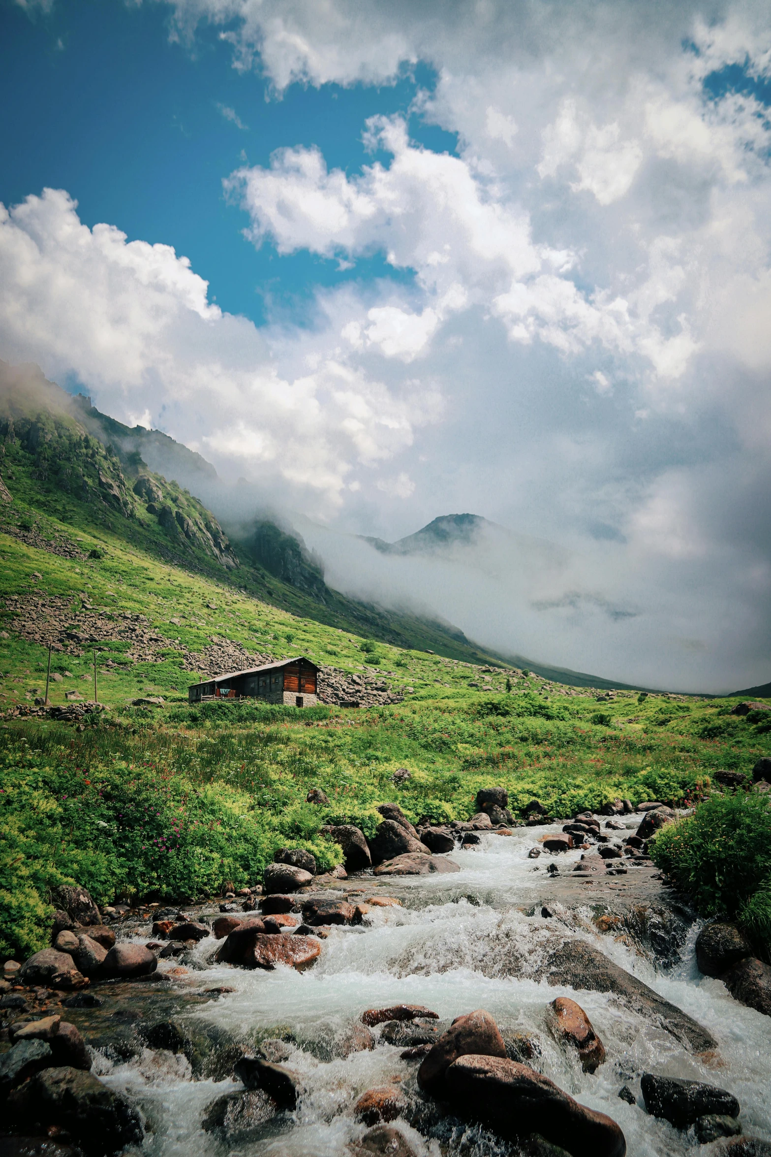 stream with house at base of mountain in foreground