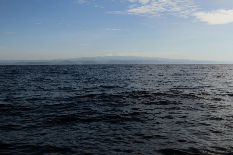 view of the horizon from the ocean with mountains in the distance