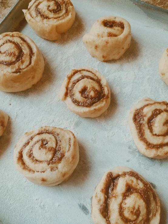a bunch of cinnamon rolls are sitting on the baking sheet