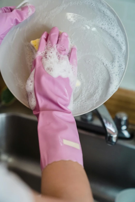 a pair of pink gloves is washing dishes in a sink