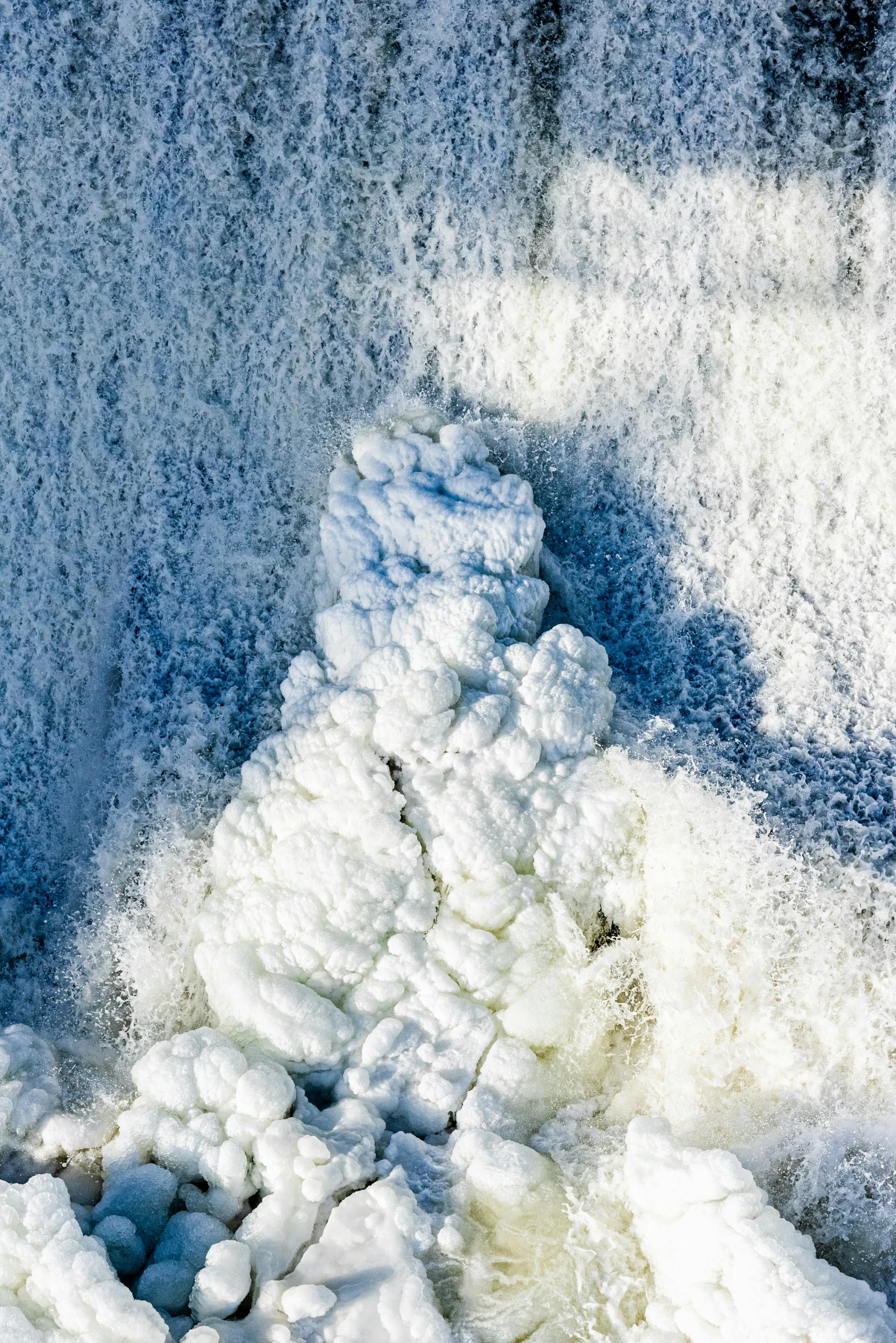 snow in front of the side of a stone wall