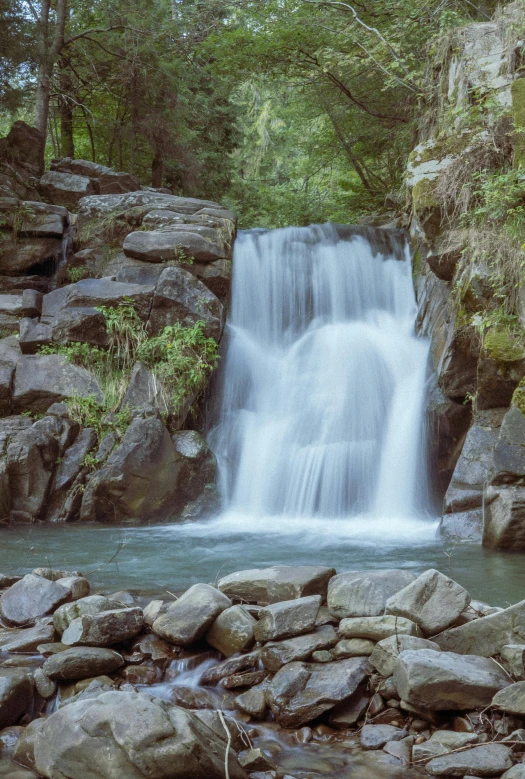 a large waterfall is seen near some rocks