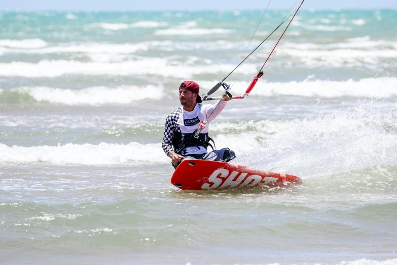 a person in the water para sailing on a red and white boat