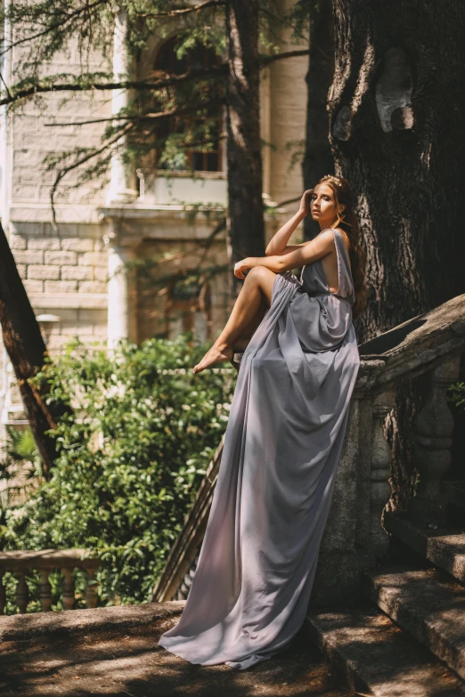 a woman poses in front of a tree