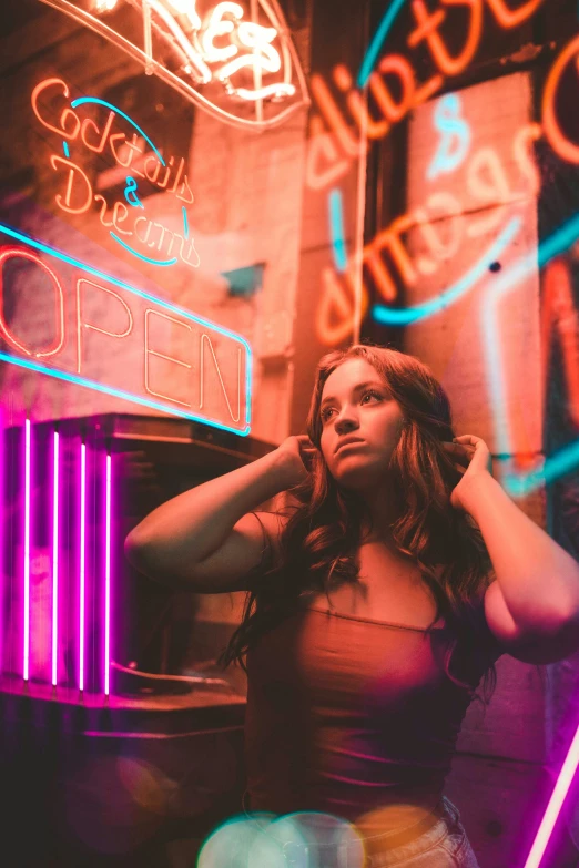a woman stands alone in front of a neon sign