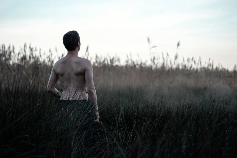 a boy standing in tall grass looking at the sky