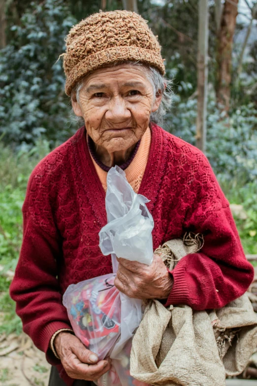 the woman wearing a knit hat is holding bags and wrapped in plastic