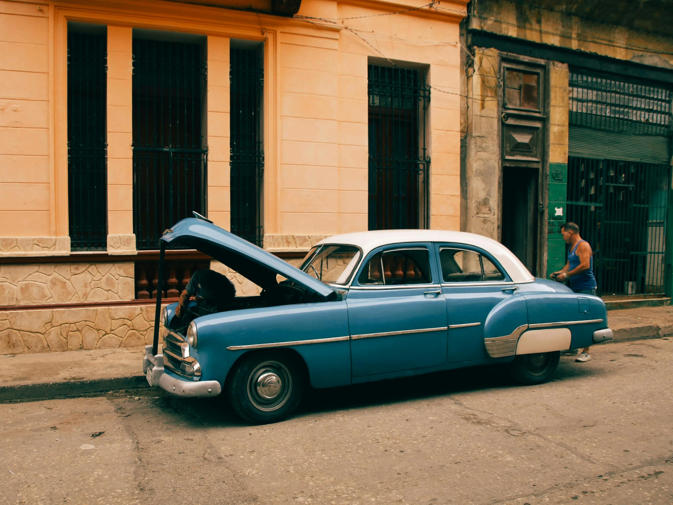 a blue car is parked on the street near a building