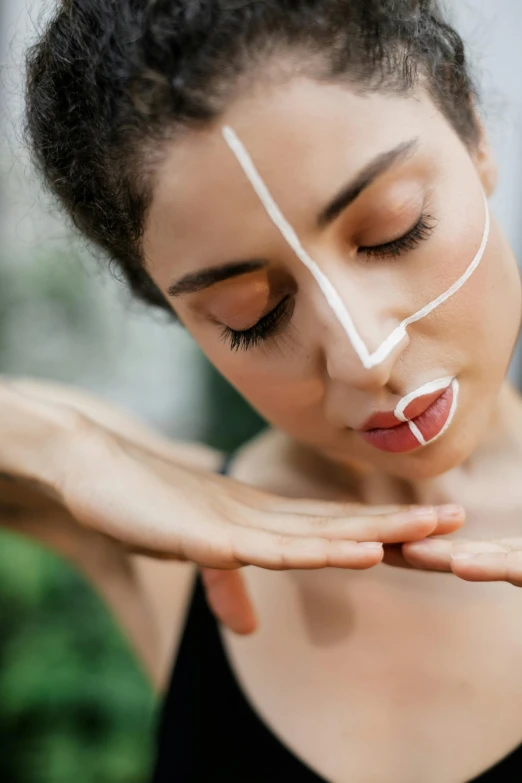 woman with thread on nose looking down at her hands