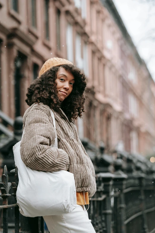 a woman standing on the street carrying a white bag