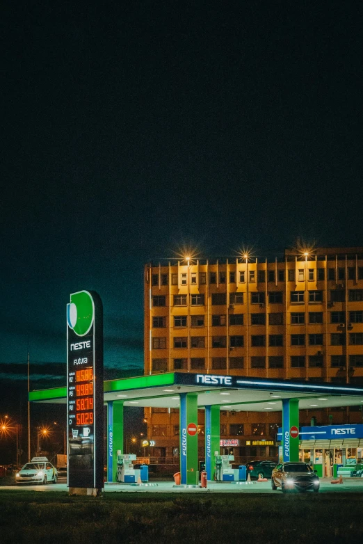 cars are at gas station near a city