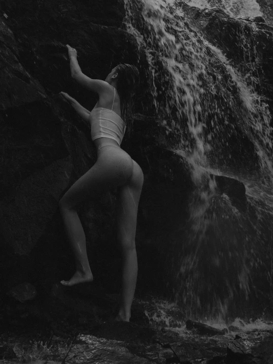 the woman is hanging upside down on rocks by a waterfall