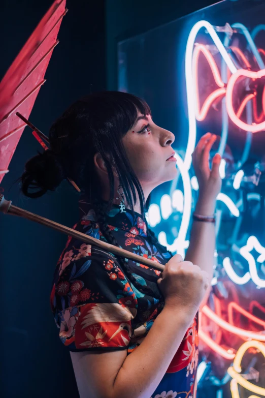 a woman holding an umbrella next to neon signs